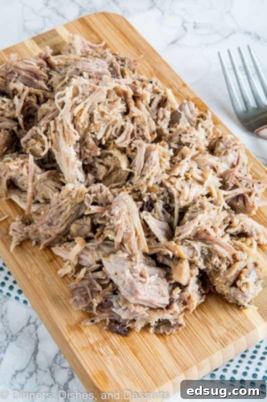 Delicious pulled pork on a wooden table, served with fresh bread and greens