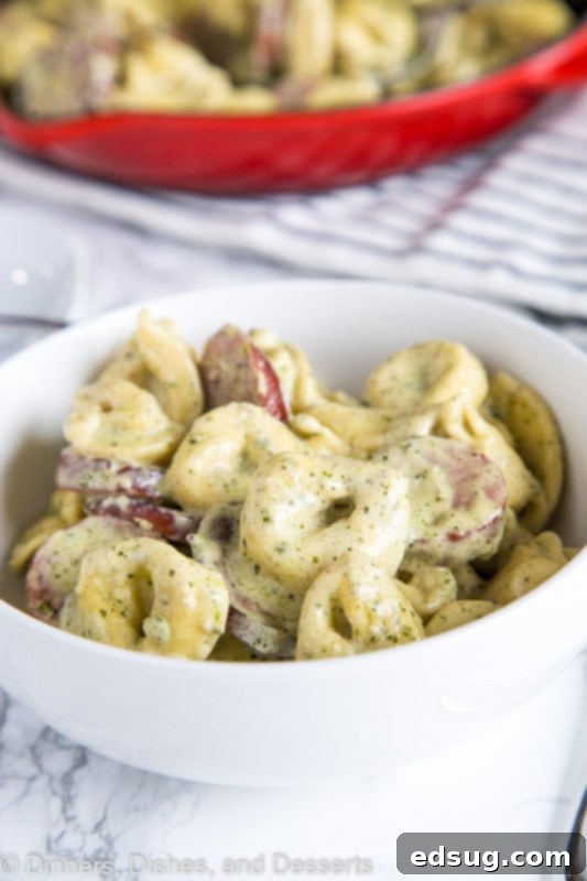 Luscious Pesto Tortellini 2 A vibrant bowl of creamy pesto tortellini with smoked turkey sausage, garnished with fresh basil and grated Parmesan.