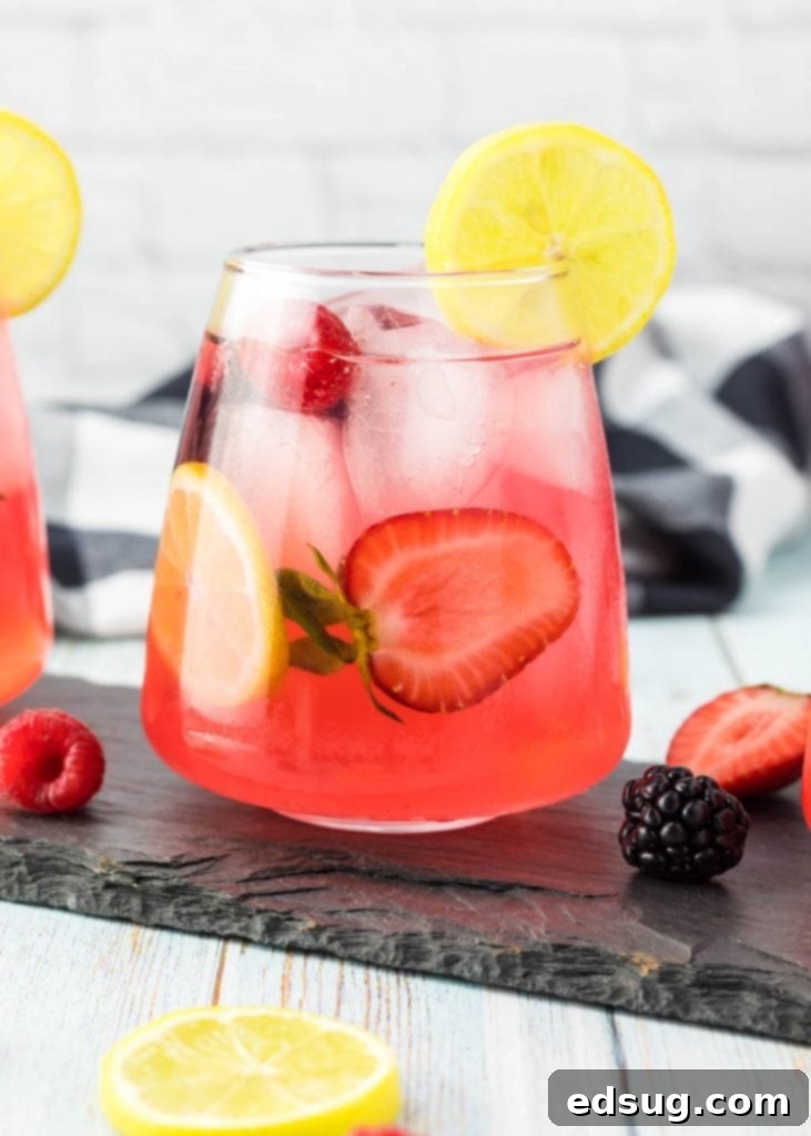 glass of sparkling lemonade with berries and a slice of lemon