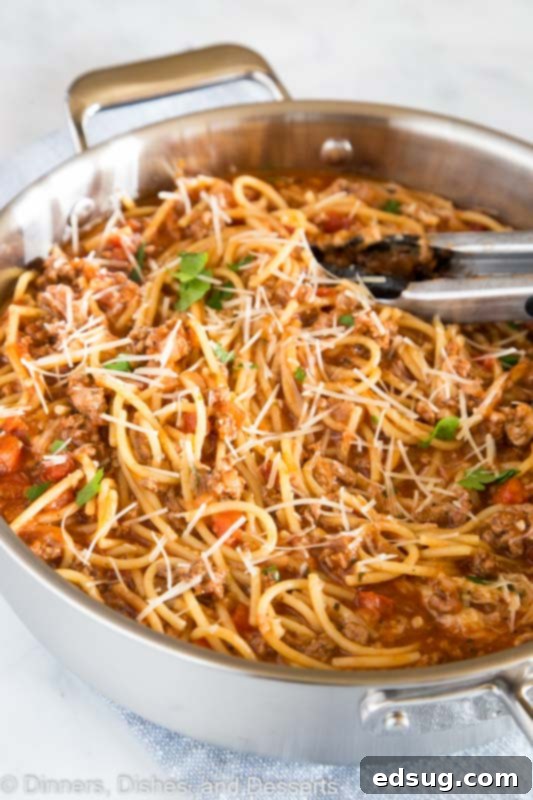 Effortless One Pot Meaty Spaghetti 2 A dish filled with steaming spaghetti and rich meat sauce, garnished with fresh herbs.