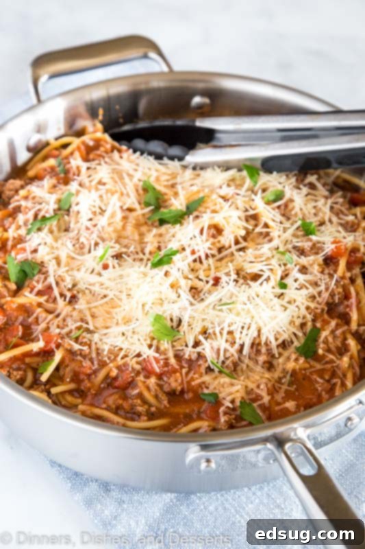 Effortless One Pot Meaty Spaghetti 5 A large pan of one-pot spaghetti with meat sauce, generously topped with shredded cheese.