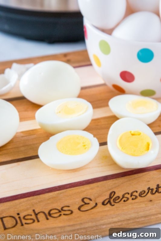 Close-up of three perfectly hard-boiled eggs, each sliced in half to show their bright, golden yolks, arranged on a wooden cutting board.