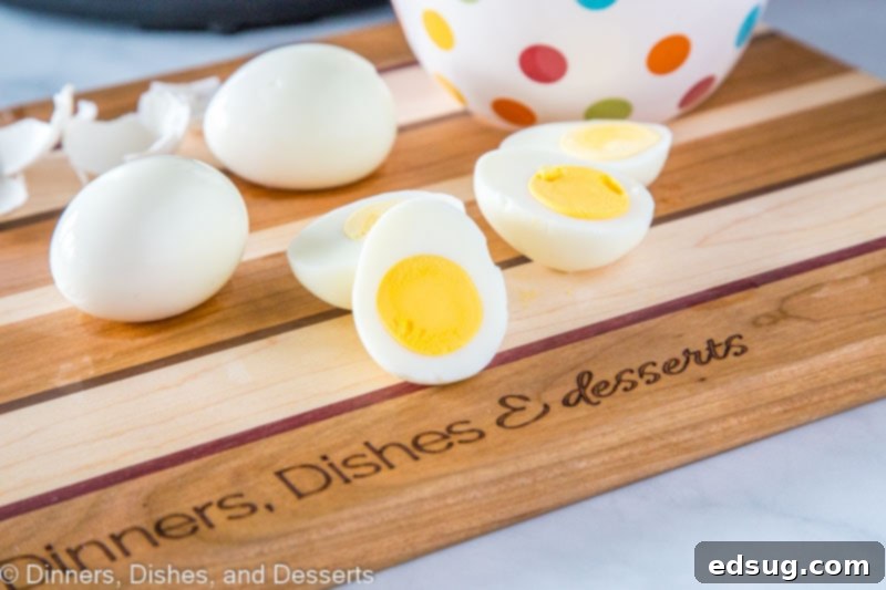 A bowl filled with whole, perfectly cooked hard boiled eggs, placed on a rustic wooden cutting board.