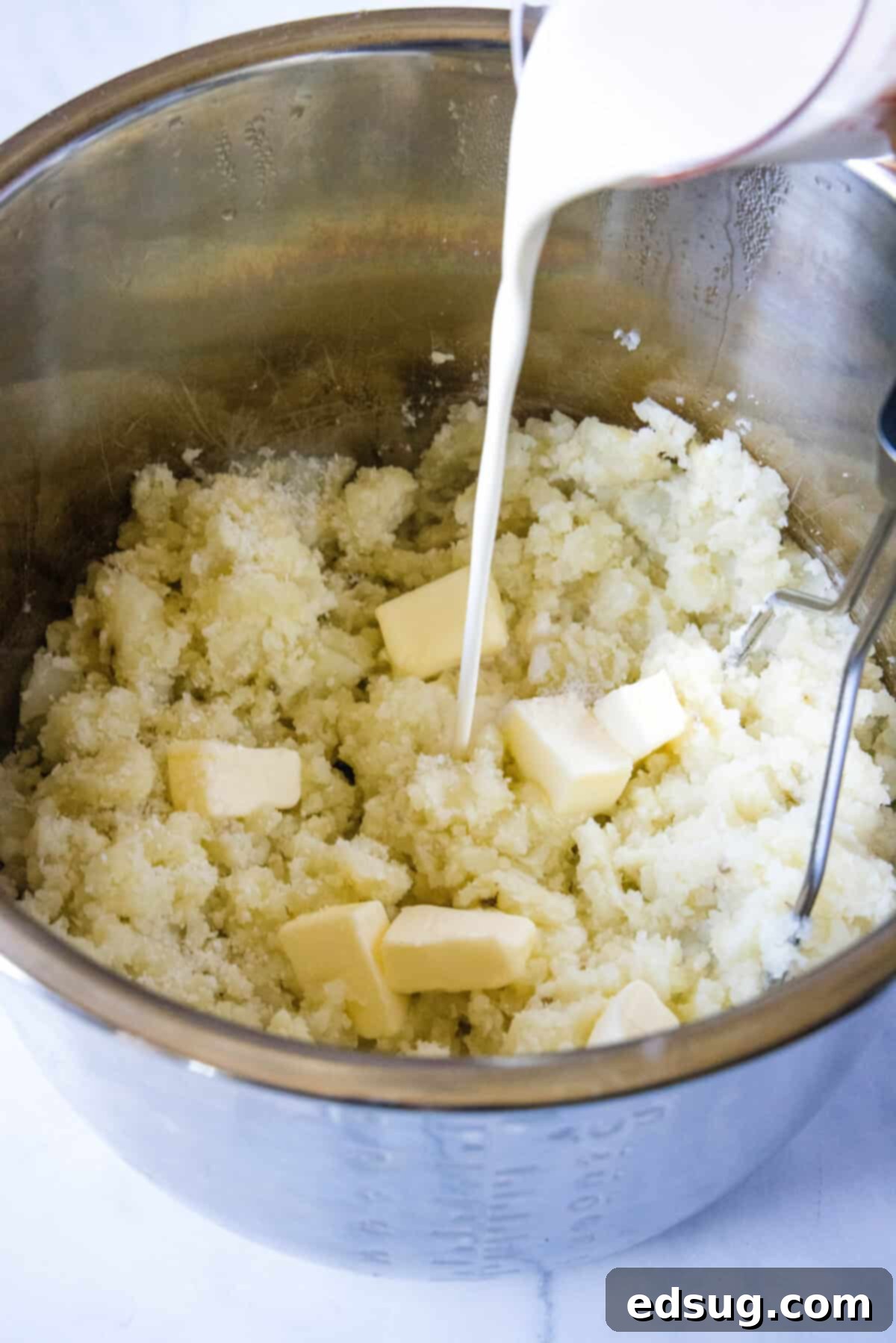 Creamy Instant Pot Mashed Potatoes 6 pouring heavy cream and butter into cooked potatoes