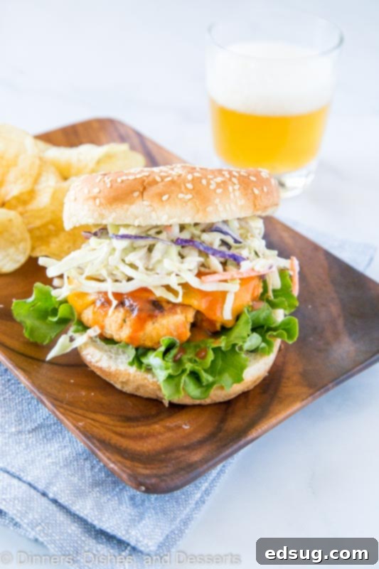 Buffalo Chicken Burger with chips on the side, showcasing a generous serving of ranch slaw and melted cheddar cheese.