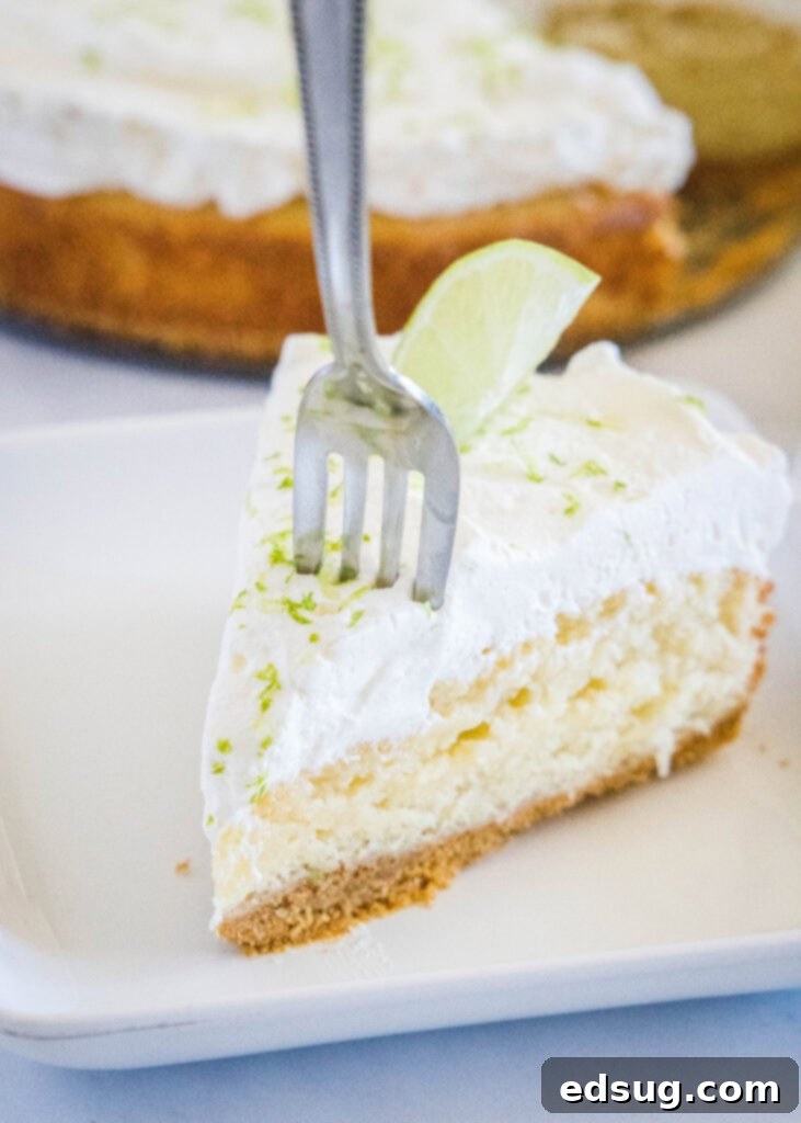 A fork taking a bite from a slice of moist Margarita Cake, garnished with lime.