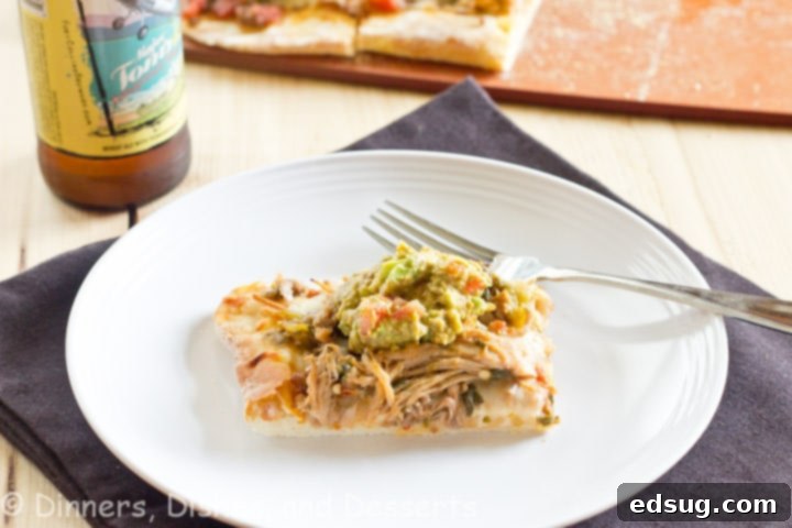 Served Carnita Pizza A large Carnita Pizza cut into slices, topped with melted cheese, pork, and fresh guacamole, ready to be served.