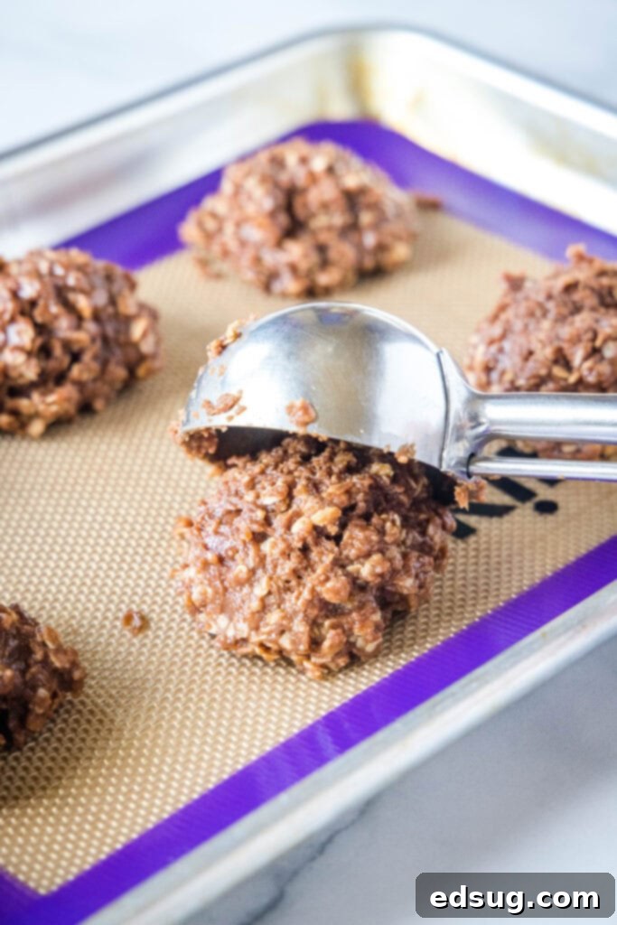 Scooping rounded portions of no bake cookie batter onto a parchment-lined baking sheet to cool and set.
