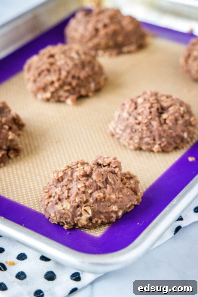 No bake cookies cooling and setting up on a parchment-lined baking sheet.