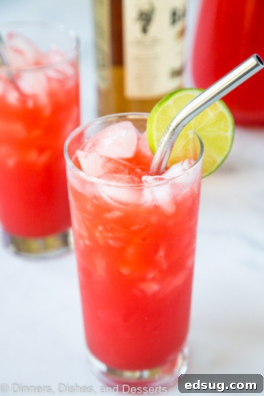Reggae Rhythm Rum Punch 3 Close-up of a glass of Jamaican Rum Punch, showcasing its vibrant red color and fresh lime garnish, ready to be enjoyed.