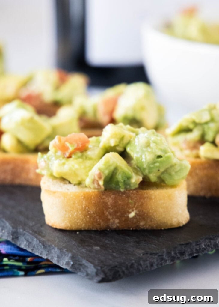 An inviting close-up of avocado bruschetta on a wooden serving board, highlighting the fresh texture of the avocado and tomato.