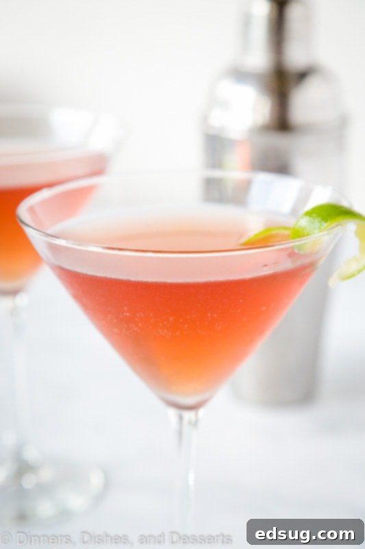 A perfectly mixed classic Cosmopolitan cocktail in a martini glass, garnished with a lime wedge, ready to be enjoyed.