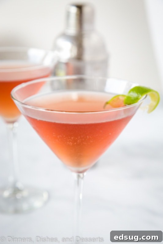 A freshly prepared Cosmo cocktail being poured from a shaker into a martini glass, illustrating the easy mixing process.