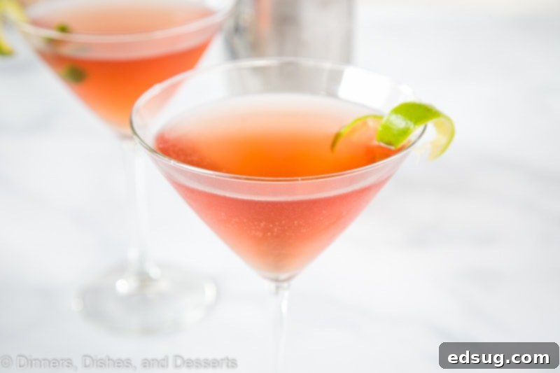 Four Cosmopolitan cocktails, garnished with lime, lined up on a bar, highlighting the beautiful pink hue.