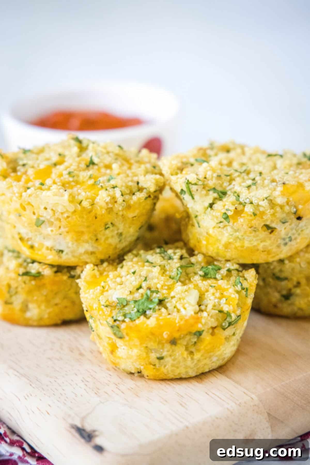cheesy quinoa bites arranged on a wooden board with a small bowl of marinara sauce