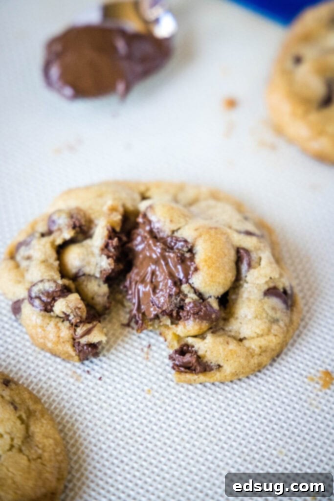 A Nutella stuffed cookie broken open, revealing the gooey center