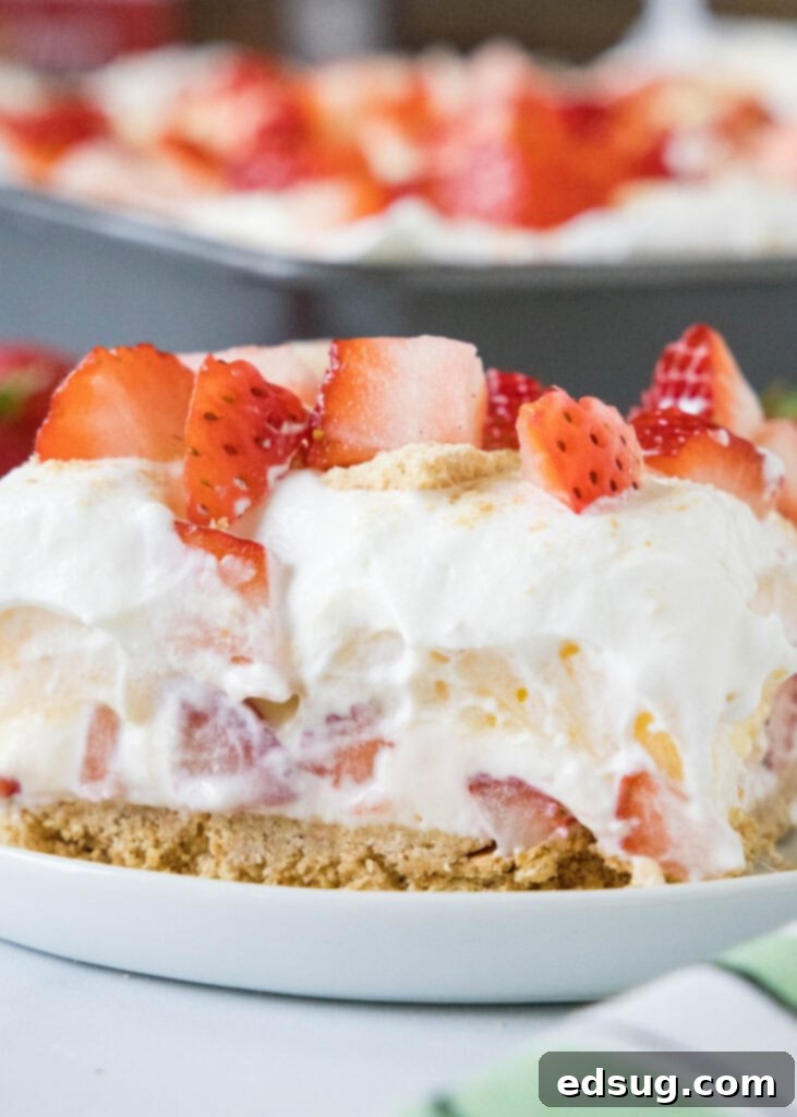 A beautifully layered strawberry lush dessert on a white plate, showcasing fresh strawberries and creamy layers.