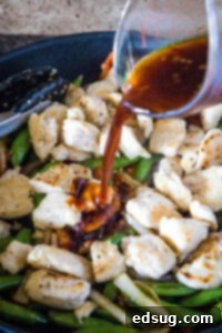 Fiery Chicken Stir Fry 11 adding sauce to chicken stir fry in a skillet