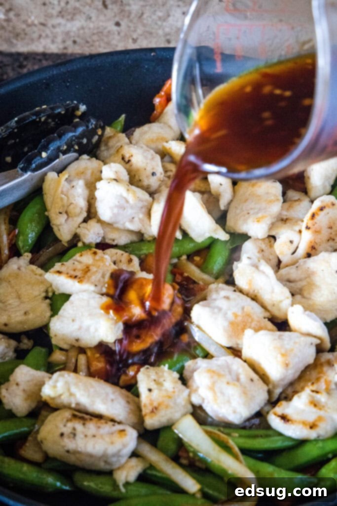 Fiery Chicken Stir Fry 5 Pouring the sweet and spicy sauce over chicken and vegetables in a skillet