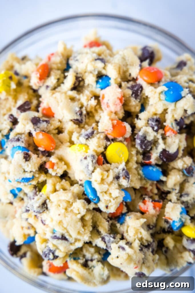 A bowl of M&M cookie dough, showcasing the colorful candies and chocolate chips mixed in