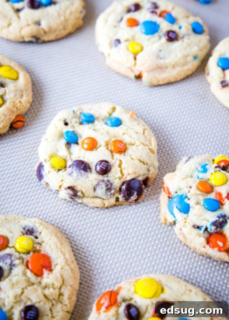 M&M cookies cooling on a baking sheet, with some already perfectly set
