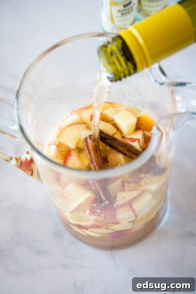 Bubbly Autumn Sangria 4 pouring white wine into a pitcher over chopped apples