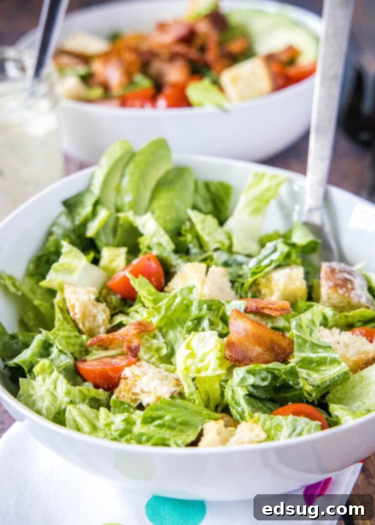 Close-up of a perfectly tossed BLT salad in a large bowl, highlighting the vibrant colors and textures of the ingredients coated in creamy dressing.