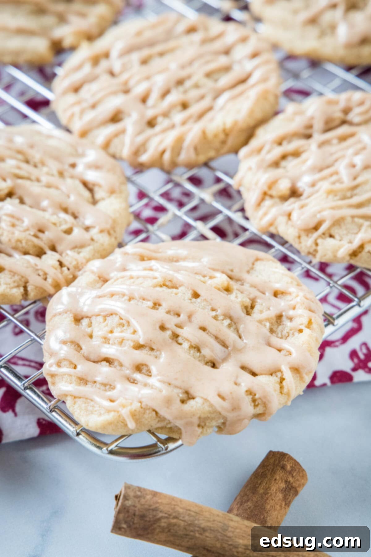 Apple Cider Cookies 3_ Apple cider cookies drizzled with cider glaze on a wire rack next to cinnamon sticks.