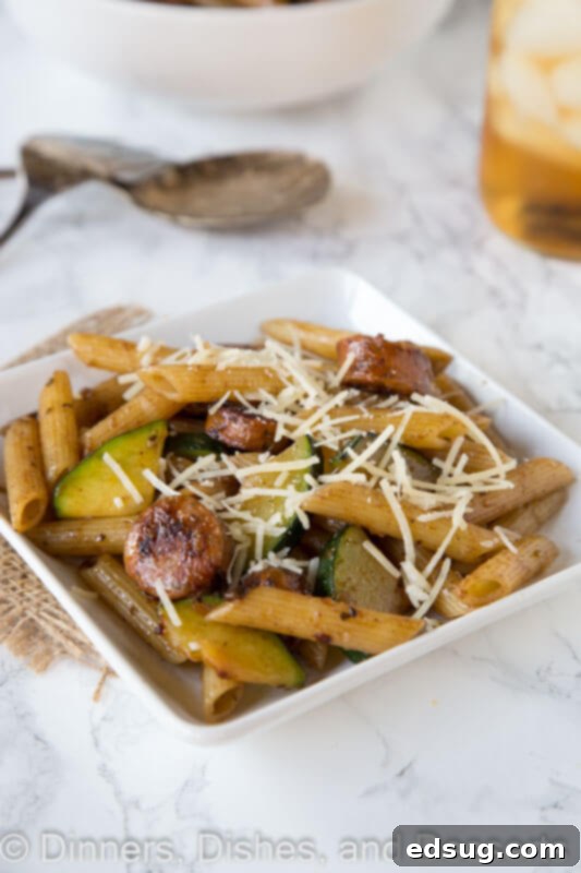 A top-down view of a fork twirling balsamic pasta with chicken sausage and vegetables, emphasizing the delicious textures and colors of the meal.