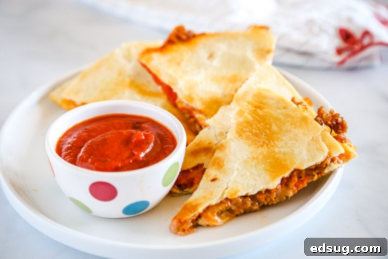 Various Pizza Quesadilla slices arranged on a cutting board with dipping sauce and fresh basil.