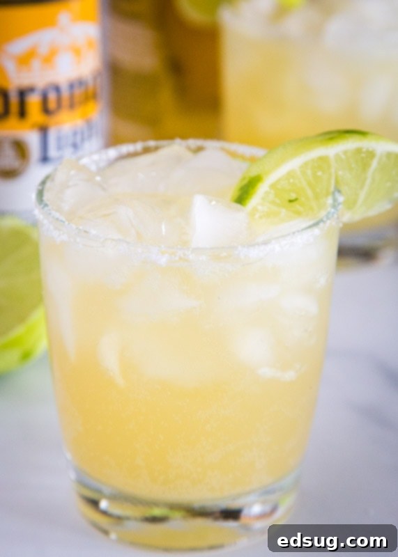 The Ultimate Beer-Garita 2 A chilled glass of light and refreshing Beer Margarita, garnished with a lime wedge, ready to be enjoyed at home.