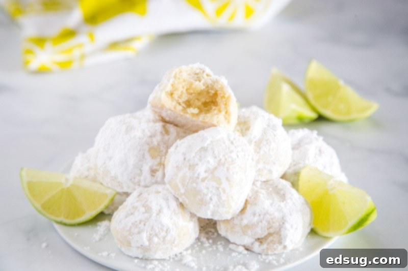 Zesty Lime Cooler Cookies 4 Freshly baked Lime Cooler Cookies with a dusting of powdered sugar, arranged on a cooling rack.