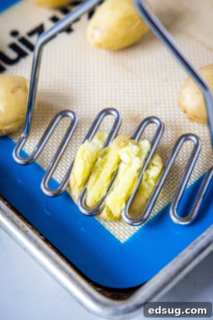 Smashed Potato Perfection 4 using a potato masher to smash potatoes