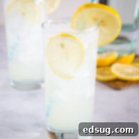 A pristine Tom Collins cocktail, perfectly mixed with gin, lemon, simple syrup, and club soda, garnished with a lemon wheel.