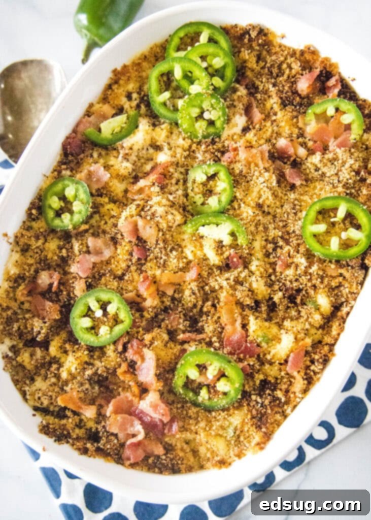 Large casserole dish of creamy Jalapeño Popper Mac and Cheese, topped with crispy bacon and fresh sliced jalapeños, ready to serve.