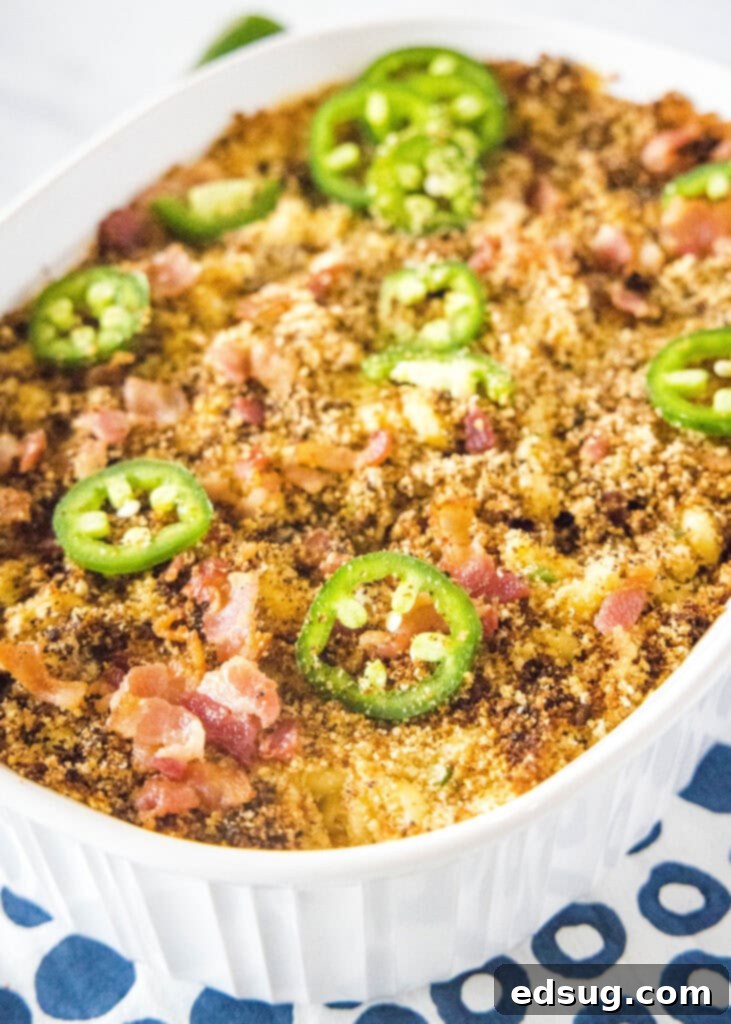 A wide shot of a casserole dish filled with bubbling, baked Jalapeño Popper Mac and Cheese, showcasing its golden crust and creamy interior.