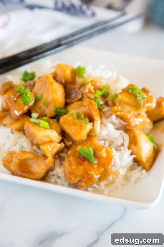 General Tso's Crispy Classic 2 A bowl of homemade General Tso chicken with green onions, served over white rice, showcasing a delicious and lighter takeout alternative.