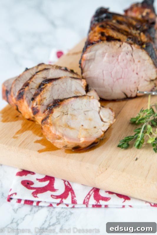 Succulent Herb-Marinated Grilled Pork Tenderloin 4 Beautifully sliced herb grilled pork tenderloin arranged on a serving platter, garnished with fresh thyme sprigs and lemon wedges, ready to be enjoyed.
