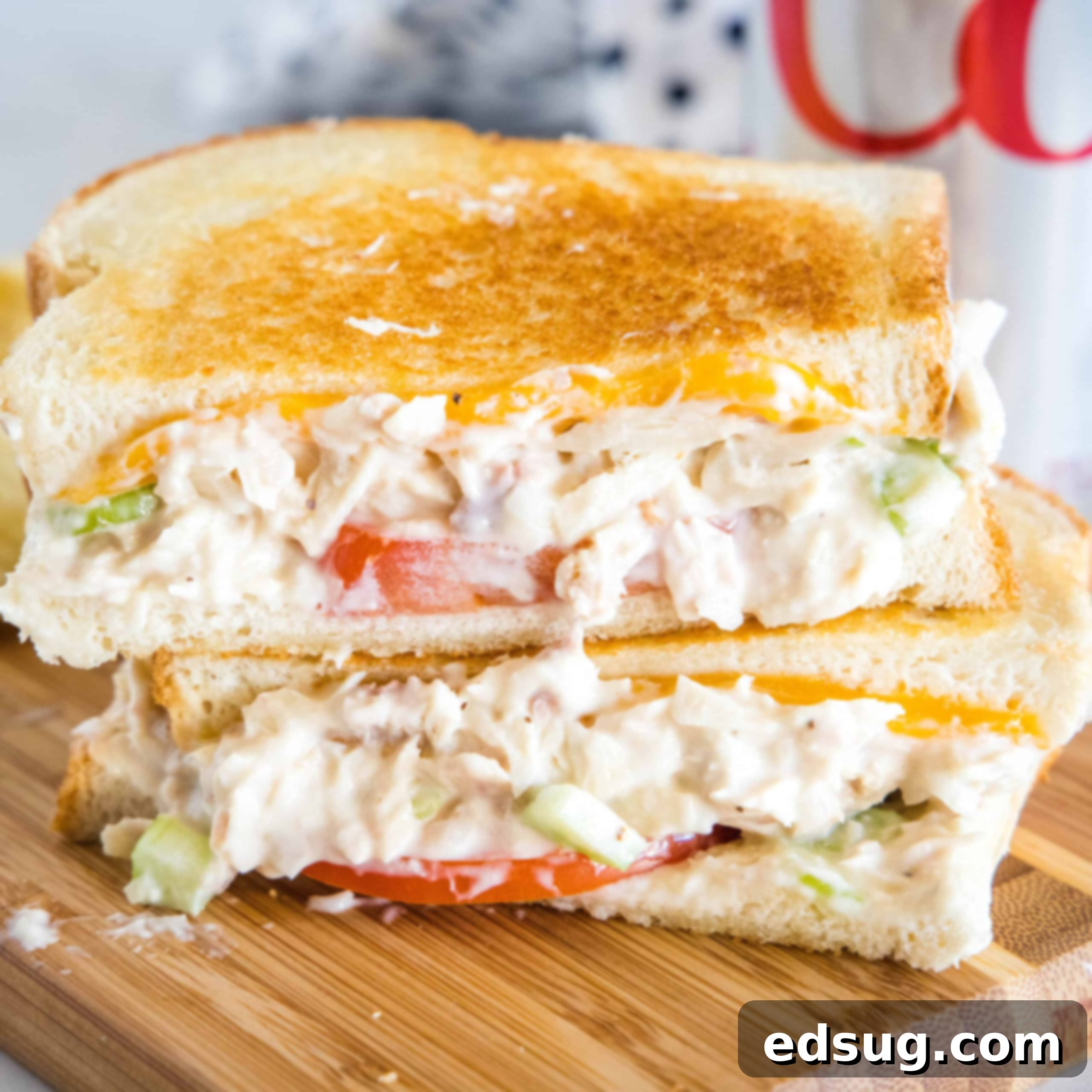 Two halves of a tuna melt stacked on top of one another on a wooden platter.