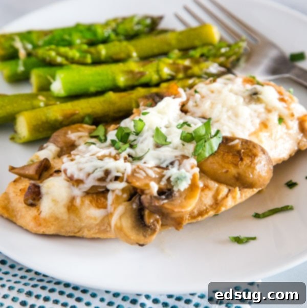 A beautifully plated Chicken Madeira with tender chicken, mushrooms, and asparagus, topped with melted cheese.
