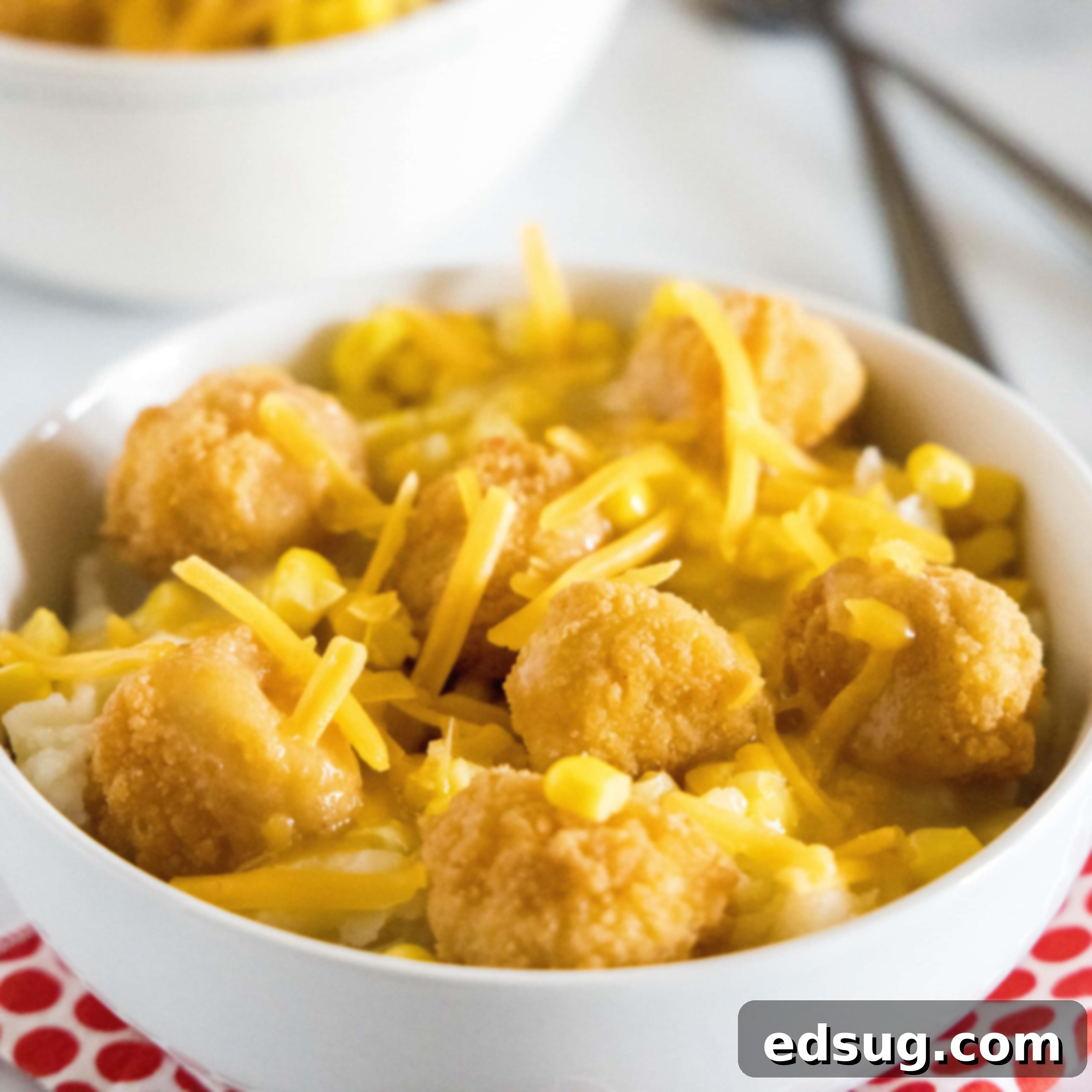 A close-up of a hearty Copycat KFC Bowl, featuring layers of mashed potatoes, chicken, corn, gravy, and cheese.