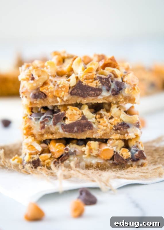 The Ultimate Layered Bars 2 Seven layer bars stacked, showcasing rich layers of chocolate, butterscotch, coconut, and nuts on a golden graham cracker crust