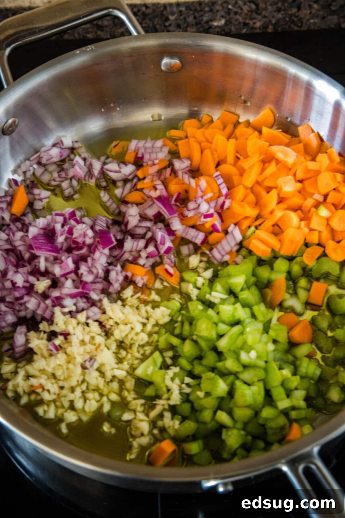 Finely diced carrots, celery, and onion gently sautéing in olive oil in a large skillet, forming the aromatic soffritto base for the ragu.