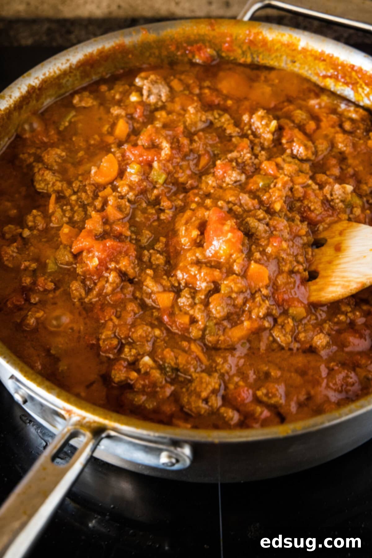 A large deep skillet filled with hearty beef ragu, gently simmering, allowing the flavors to meld and deepen.