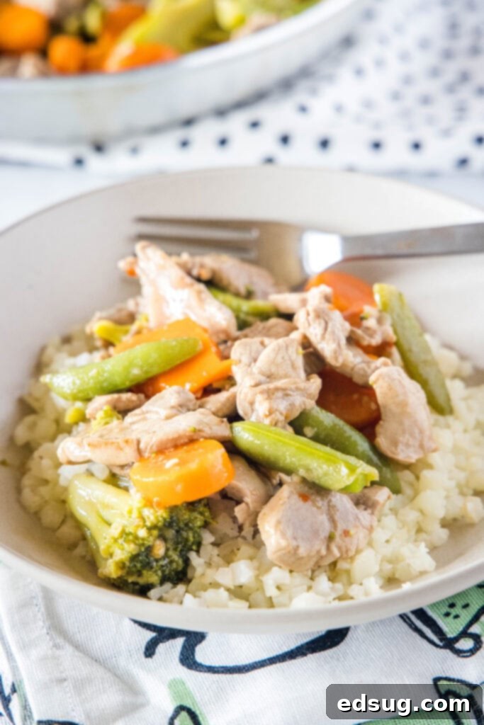 pork stir fry served over rice in a white bowl
