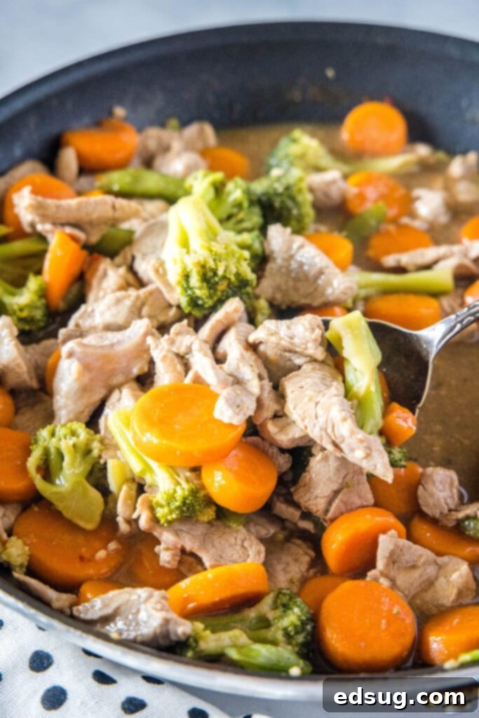 scooping pork stir fry from the skillet