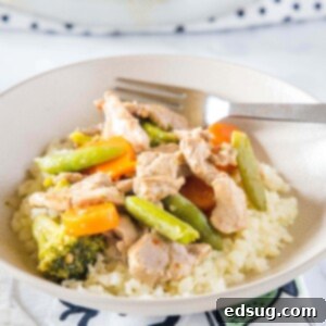 cropped close up of pork stir fry with veggies in a white bowl with rice