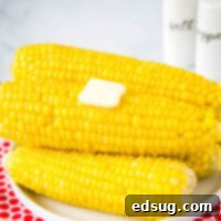 pressure cooker corn on the cob stacked on a white plate with pat of butter on top