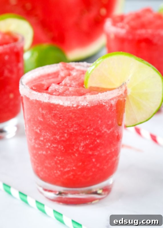 Fresh Watermelon Margaritas 2 Two glasses of frozen watermelon margaritas garnished with lime wedges and fresh watermelon cubes.