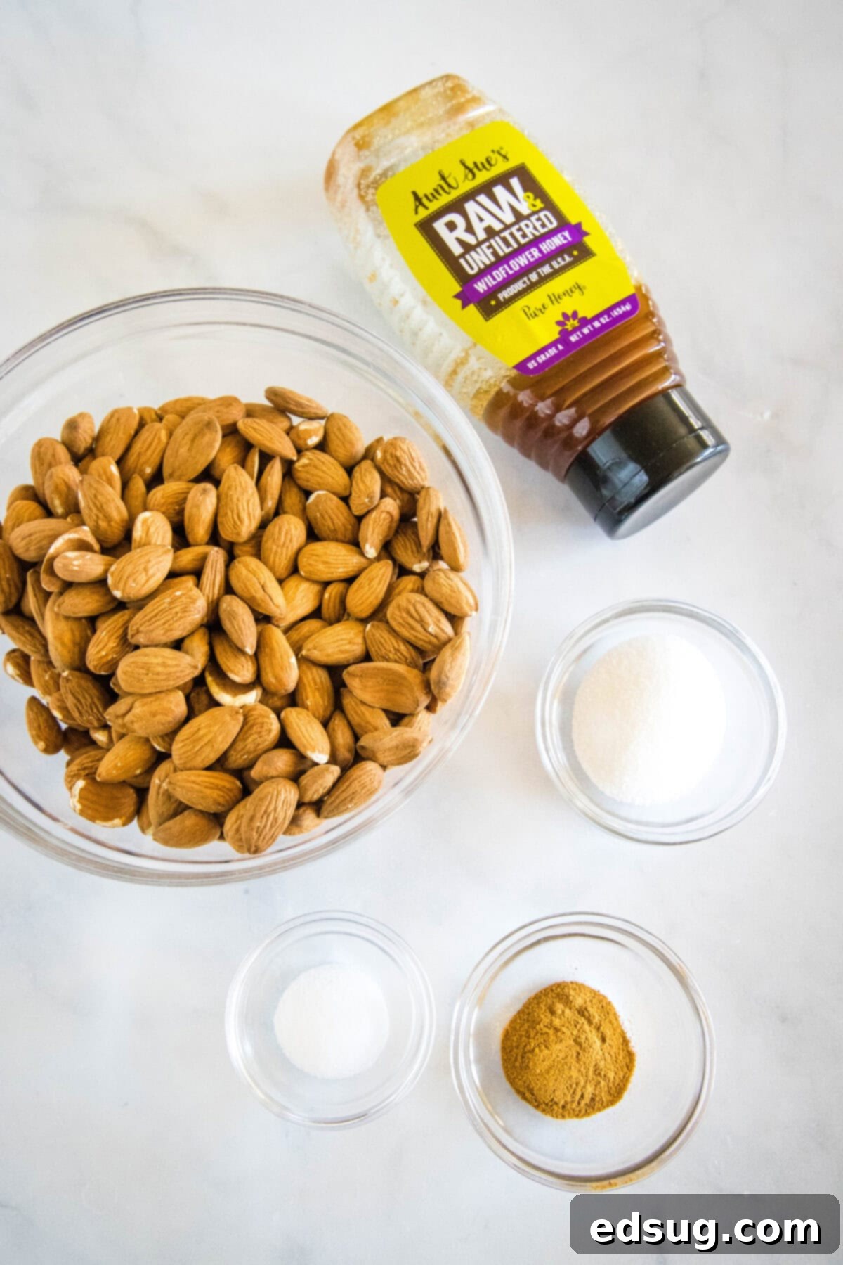 Sweet Heat Honey Roasted Almonds 2 Close-up shot of the five simple ingredients laid out on a wooden board: almonds, honey, cayenne pepper, sugar, and salt.